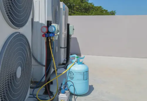 Air conditioning service technician using gauges to check refrigerant and add refrigerant.