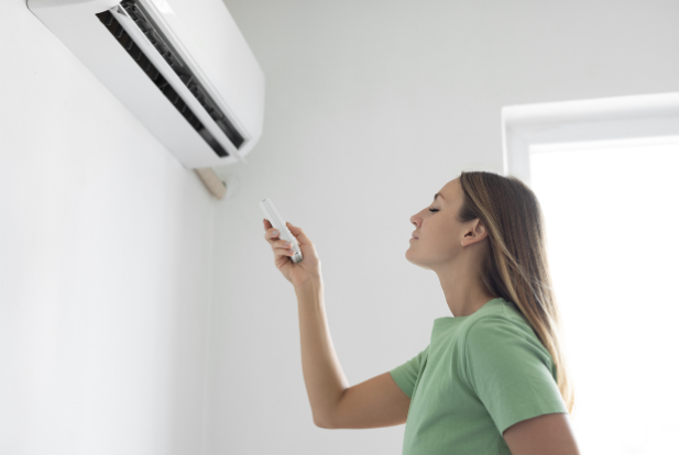 Woman turning on air conditioner.