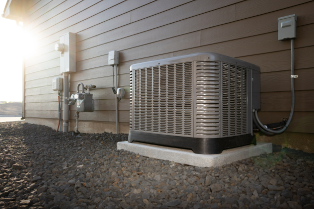 Modern air conditioning unit with two-stage compressor on a concrete slab outside of a duplex house.