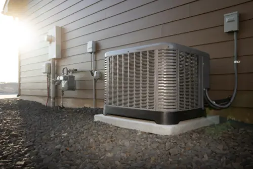 Modern air conditioning unit with two-stage compressor on a concrete slab outside of a duplex house.